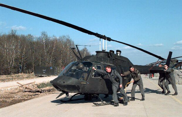 Image: Chief Warrant Officer Chris Elam gets help pushing his OH-58 Kiowa helicopter.