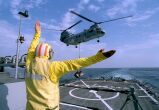 Image: Petty Officer Brown directs a CH-46 Sea Knight toward the flight deck of the USS John S. McCain.