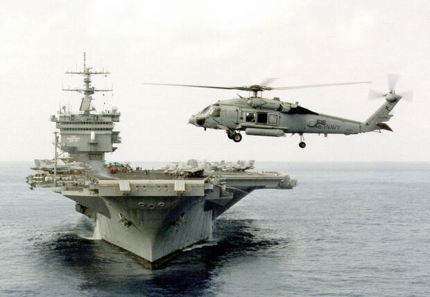 Image: An SH-60 helicopter hovers off the bow of USS Enterprise CVN 65.