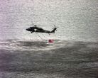 Image: An Army Blackhawk helicopter fills a 700 gallon water bucket to fight forest fires in Florida.