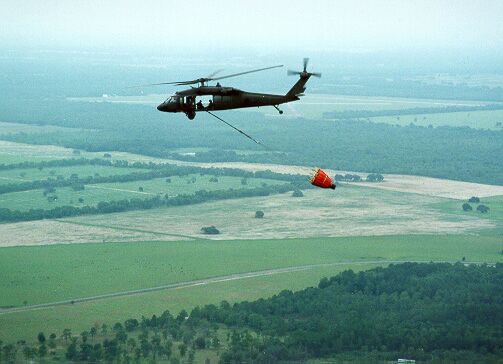 Image: A Blackhawk helicopter carries a 700 gallon water bucket to fight forest fires.