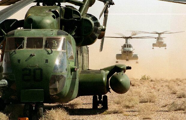 Image: CH-46 Sea Knights stir up a cloud of dust as they launch behind a CH-53 Sea Stallion.